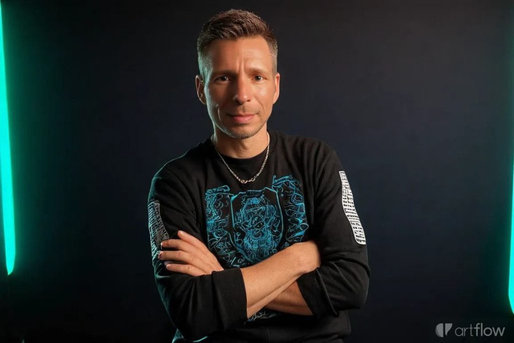 Portrait Mann mit verschränkten Armen, lächelt vor dunktem Hintergrund mit grünen Lichtern.